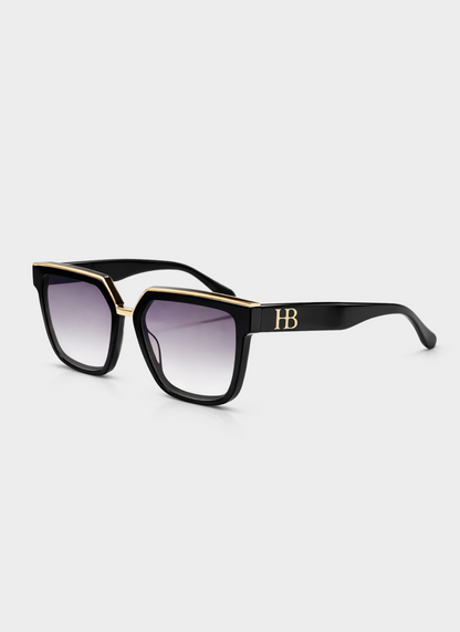 Black sunglasses with gold accents on a light gray background