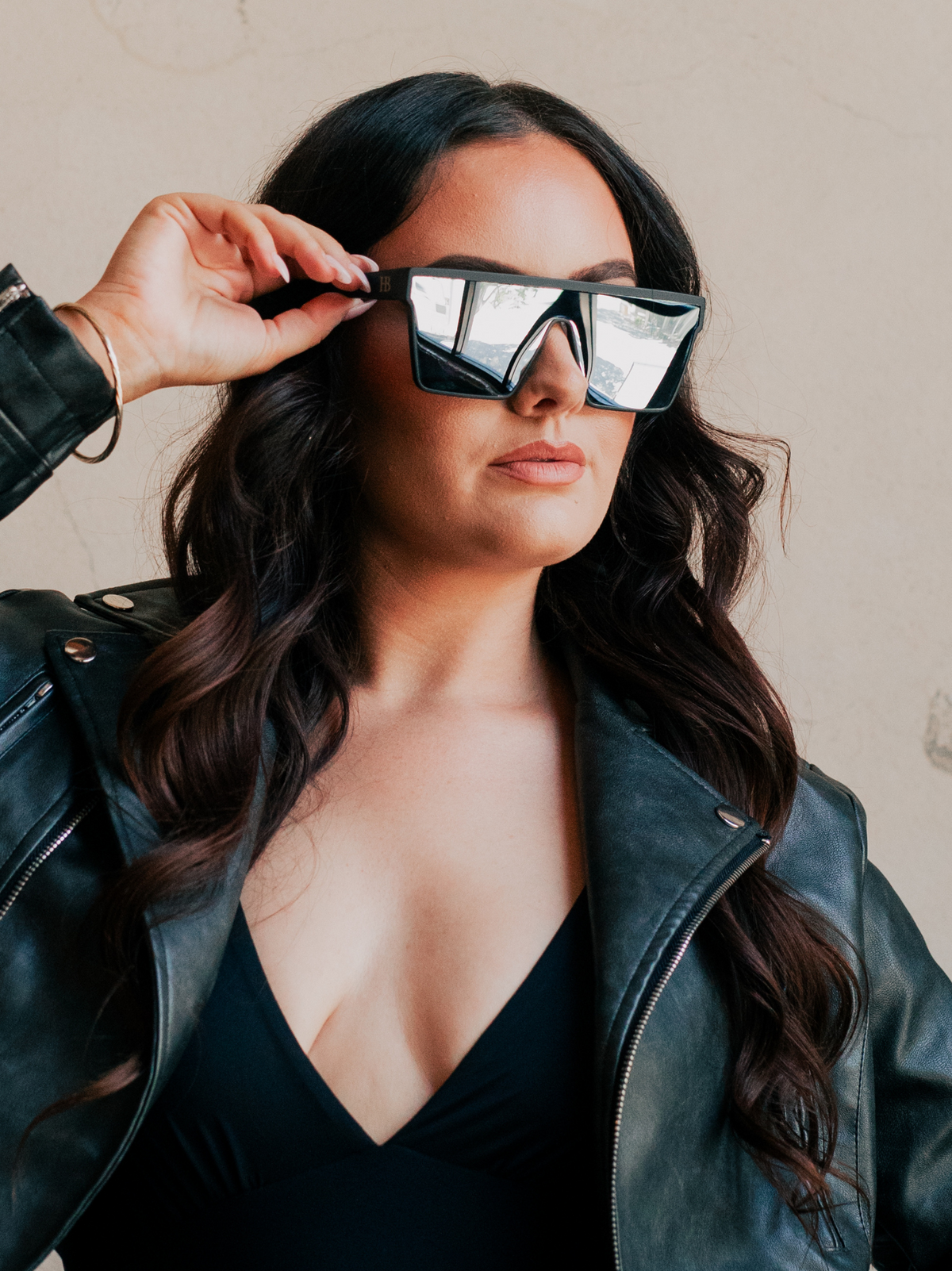 Woman wearing reflective sunglasses and a black leather jacket.